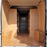 Large van interior fitted with deep wooden shelving on both sides, showing six storage sections per side and wide central access space by Ply Van Racking Ltd